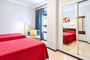 Ein Hotelzimmer mit zwei Betten, einer Schlafcouch, einer Lampe und einem großen Spiegel.
