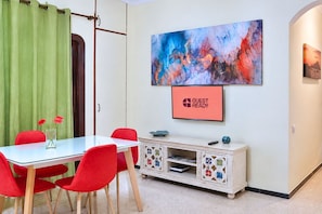 A room with a dining table, red chairs, a cabinet with decorative tiles, a painting, and a 'GUEST READY' sign. - GuestReady - DiMar Sea View Premium (Las Palmas de Gran Canaria)