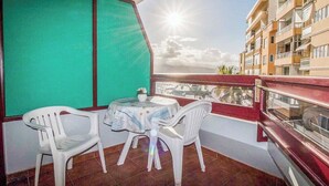 A balcony with a table and chairs, a view of the sea, and a building in the background. - GuestReady - DiMar Sea View Premium (Las Palmas de Gran Canaria)