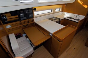 A compact kitchen with a stove, sink, and storage cabinets. - Sun-Kissed Sailing Adventure in Split, Croatia (Split)