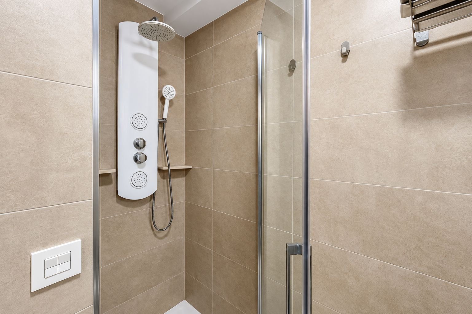 A modern shower with a handheld showerhead and a wall-mounted control panel.
