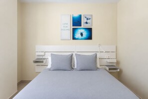 Ein Schlafzimmer mit einem Bett, zwei Kissen, einem Nachttisch und Wandbildern.
