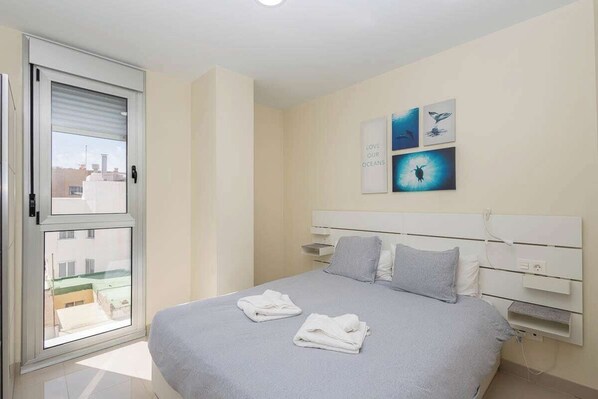 Quarto com cama, janela e obra de arte na parede.
