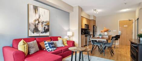 A modern apartment with a red sofa, a dining area, and a kitchen.