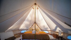 A tent with a bed, a chair, and a small table.
