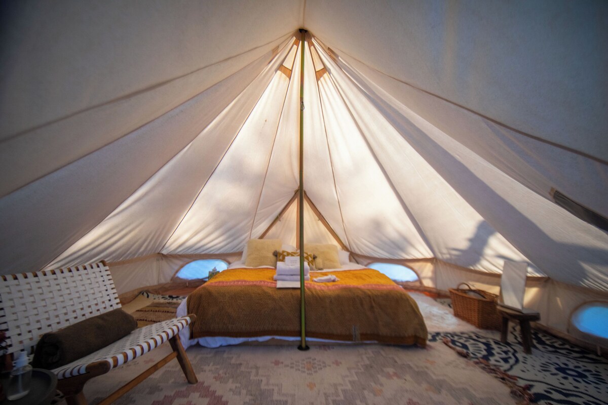 A tent with a bed, a chair, and a small table.
