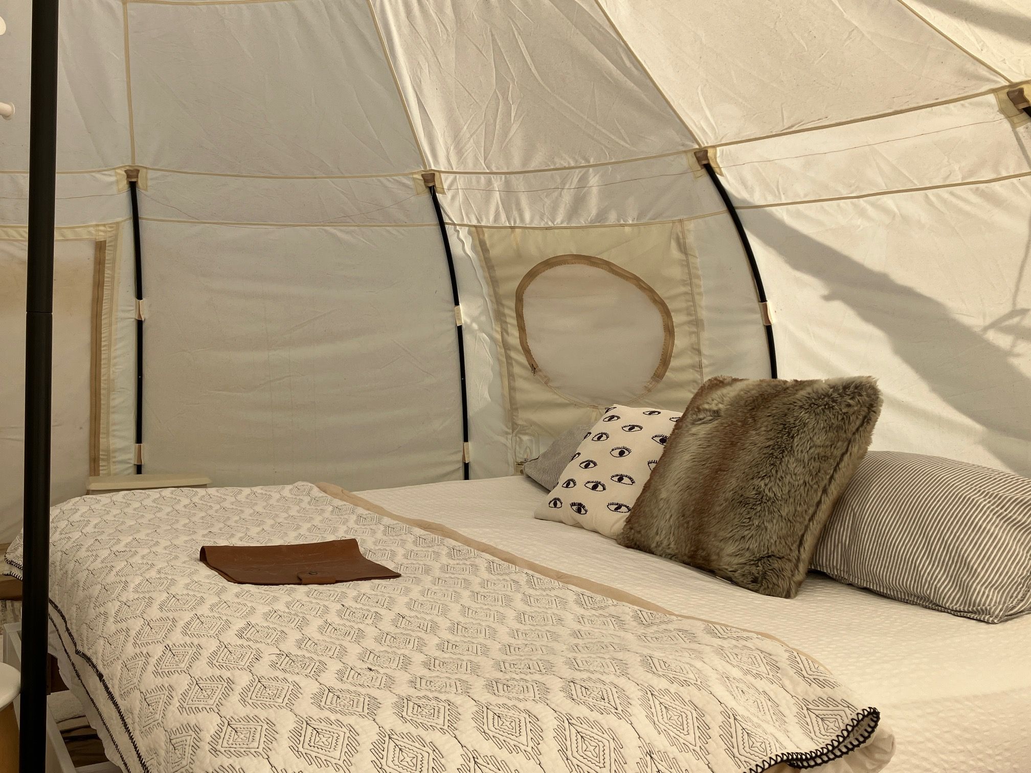 Una carpa con una cama en su interior, con ropa de cama y almohadas estampadas.
