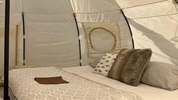 Una carpa con una cama en su interior, con ropa de cama y almohadas estampadas.