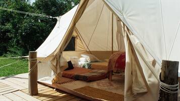 A tent with a bed inside, a small window, and a wooden deck.