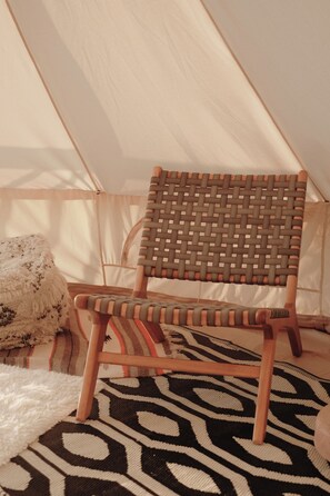 A tent with a woven chair and a patterned rug inside.