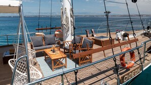 Um terraço com assentos, uma mesa e vista para o mar.