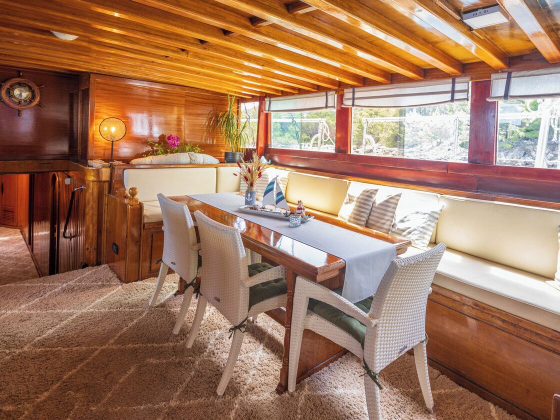 Un interior de madera con una mesa de comedor, sillas y un banco junto a una ventana.