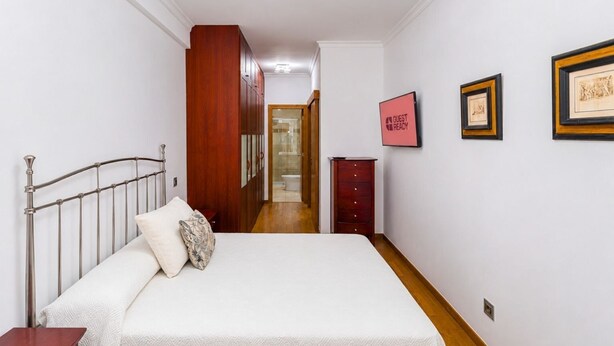Ein Schlafzimmer mit einem Bett, einem Kleiderschrank, einer Kommode und einem gerahmten Bild an der Wand.