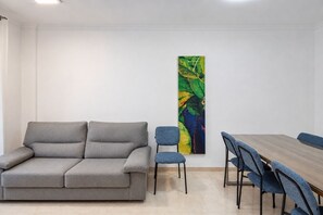 Een kamer met een grijze bank, een blauwe stoel en een houten tafel.