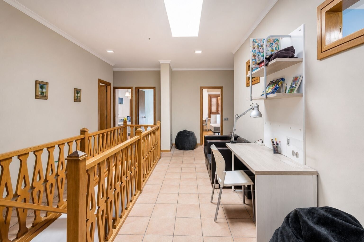 Et moderne interiør med trappe, skrivebord med stol og en reol.