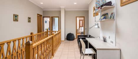 Un interior moderno con una escalera, un escritorio con silla y una estantería.