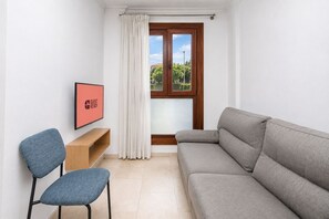 Ein modernes Wohnzimmer mit einem grauen Sofa, einem blauen Sessel, einem Holztisch und einem gerahmten Bild an der Wand.