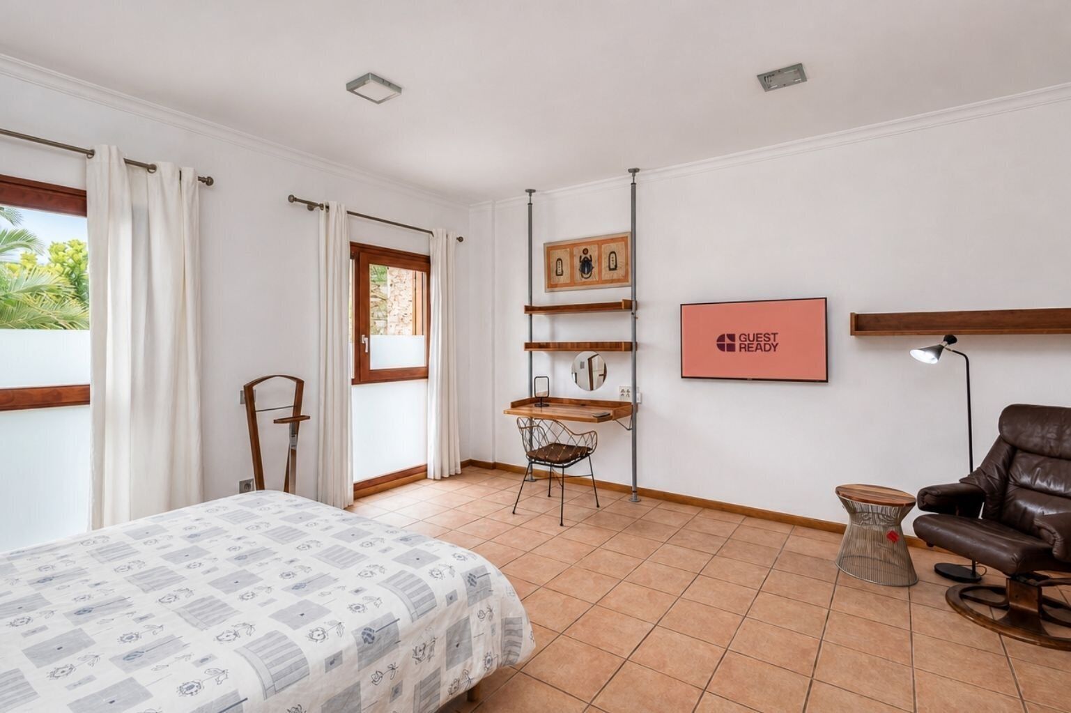 Une chambre à coucher avec un lit, un bureau, une chaise, un canapé et un panneau indiquant « CHAMBRE PRÊTE POUR LES INVITÉS ».