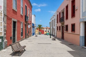 Eine enge Straße mit Häusern an beiden Seiten, Bänken und blauem Himmel.