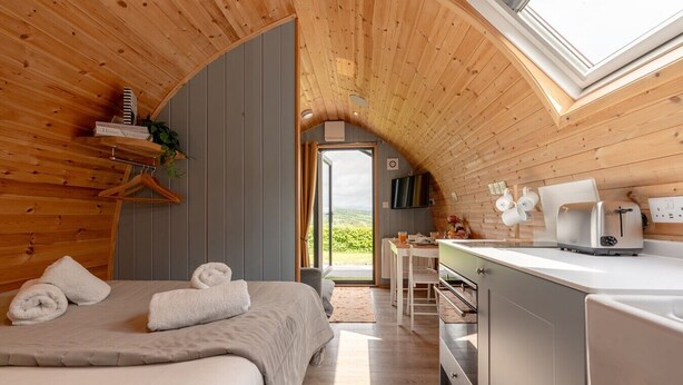 Un dormitorio cálido en el ático, con una cama, una mesita y un rincón de cocina.