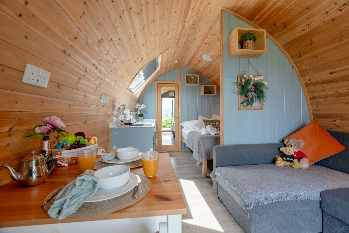 A cozy cabin interior with a dining area, a sofa, and a bed.