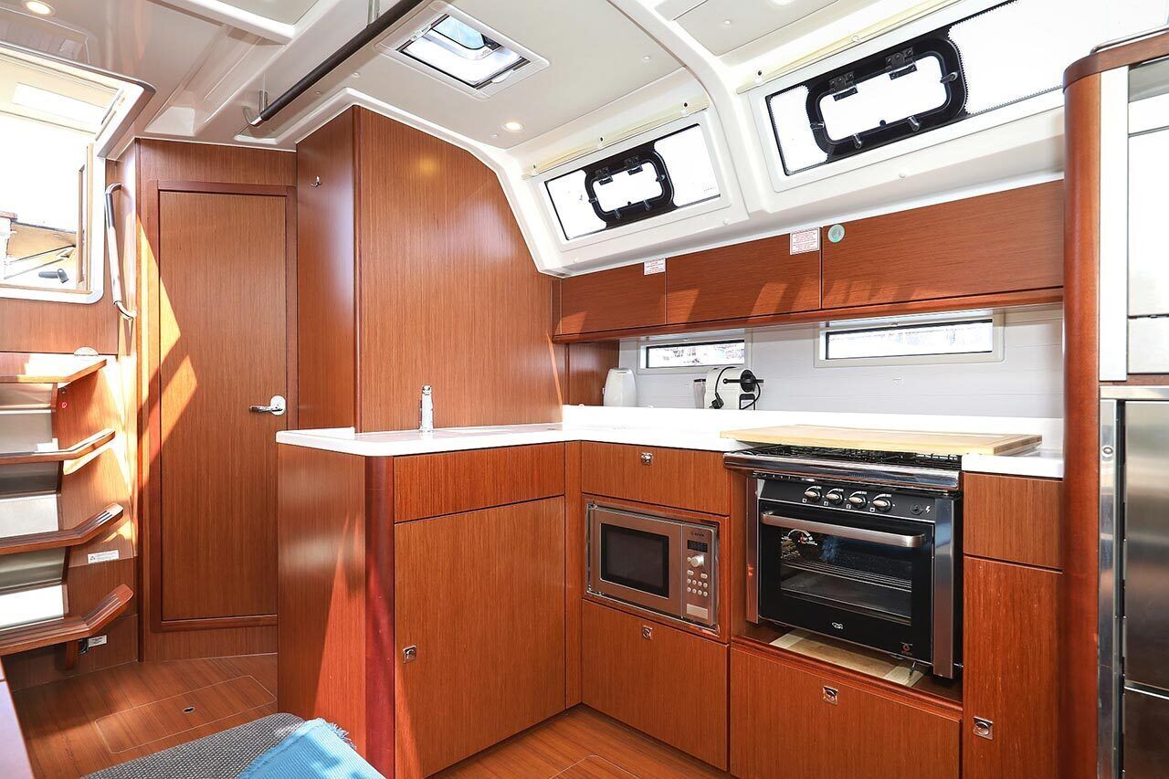 Une cuisine compacte avec des meubles en bois, un four encastré, un four à micro-ondes et un petit plan de travail.