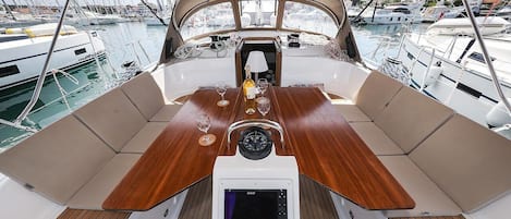 A boat's deck with a wooden table, a digital device, and a bottle of champagne.
