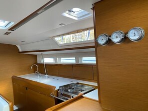 A compact kitchen with a gas stove, a sink, and a window with skylights. - Sun-Kissed Sailing Adventure in Islas Baleares, Mallorca (Palma)