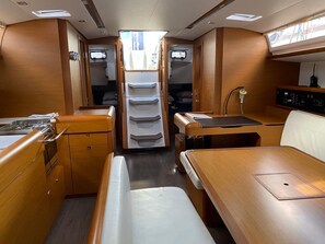 A compact interior with a dining area, a small kitchenette, and a seating area with a view through a door. - Sun-Kissed Sailing Adventure in Islas Baleares, Mallorca (Palma)