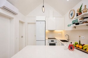 A modern kitchen with white cabinetry, a central island, and a fruit bowl. - GuestReady - Los Tunos BBQ Garden (San Bartolomé de Tirajana)