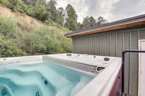 A hot tub with a wooden deck, surrounded by a hillside and trees. - Pigeon Forge Cabin w/ Swim Spa: Walk to Dollywood! (Pigeon Forge)