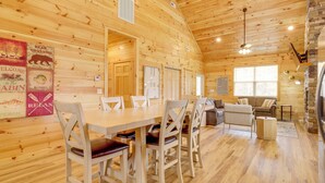 A wooden cabin interior with a dining table, chairs, a sofa, and a fireplace. - Dolly's Cabin: Private Hot Tub, Walk to Dollywood (Pigeon Forge)