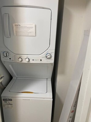 Eine Frontansicht einer Waschmaschine und eines Wäschetrockners mit einer Bedienungsanleitung obenauf.