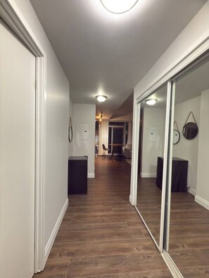 Ein Korridor mit Holzboden, weißen Wänden und einer Glastür zu einem Zimmer.