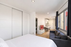 A modern hotel room with a large bed, a sofa, a TV, and a kitchenette. - GuestReady - Artiles Loft Canteras Balcony (Las Palmas de Gran Canaria)