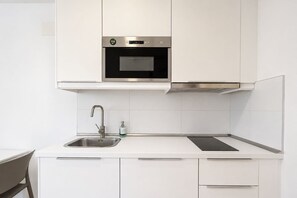 A modern kitchen with a stainless steel oven, a sink with a faucet, and white cabinetry. - GuestReady - Artiles Loft Canteras Balcony (Las Palmas de Gran Canaria)