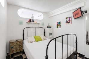 A bedroom with a bed, bedside table, and a shelf with books. - GuestReady - San Agustin Pool Escape (Playa del Ingles)