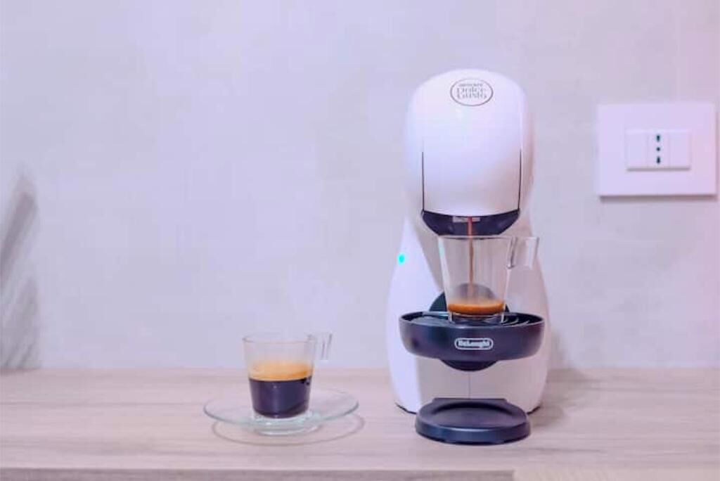 Eine Kaffeemaschine gibt Kaffee in eine Glaskanne auf einem Holztisch.