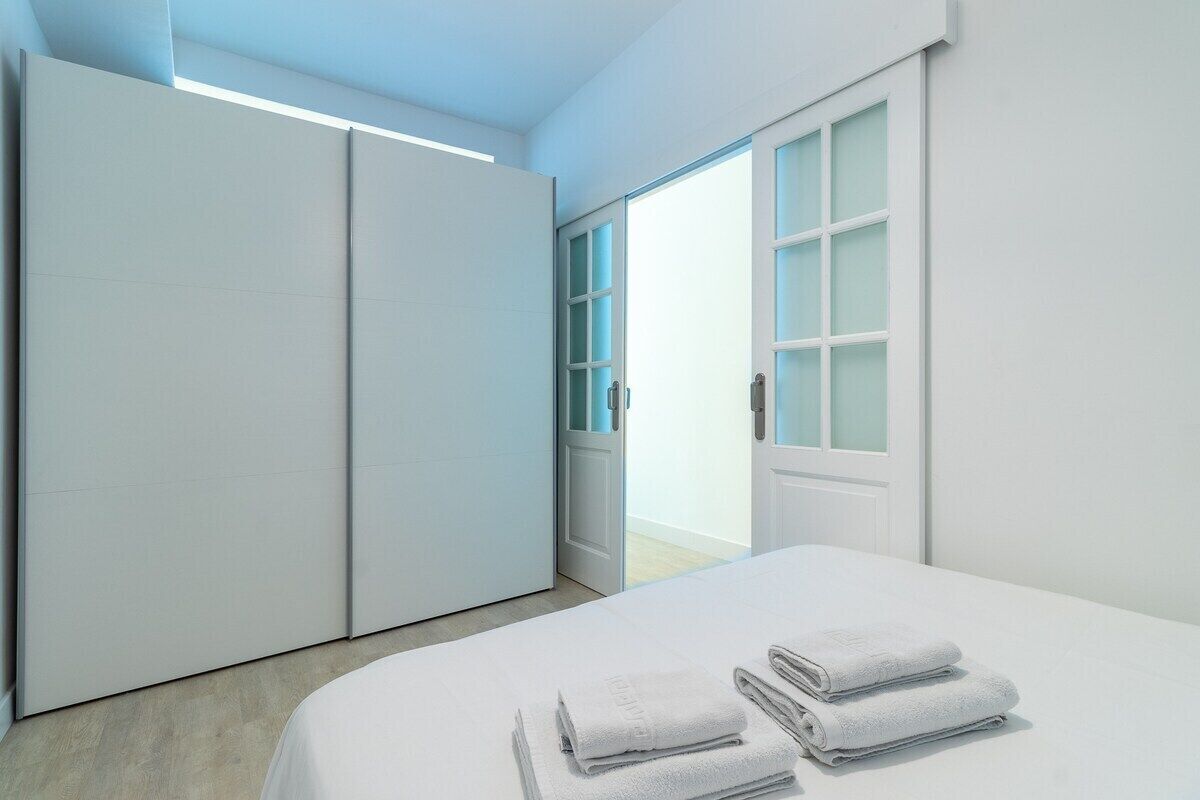 A bedroom with a bed, a wardrobe, and a door leading to a balcony.