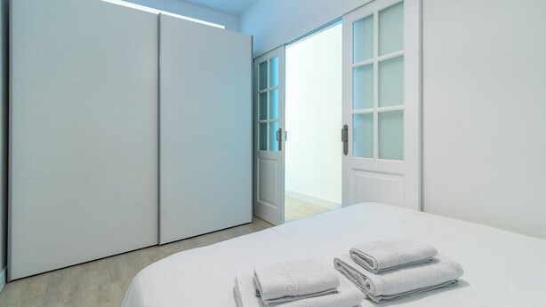 Ein Schlafzimmer mit Bett, Kleiderschrank und einer Tür, die auf einen Balkon führt.