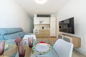 A compact living space with a kitchenette, a dining area, and a TV mounted on the wall. - GuestReady - Sunset Canteras Sea Views (Las Palmas de Gran Canaria)
