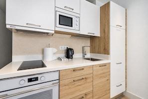 A modern kitchen with white cabinetry, a built-in microwave, a kettle, and a digital clock displaying 9:52. - GuestReady - Sunset Canteras Sea Views (Las Palmas de Gran Canaria)