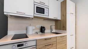 Eine moderne Küche mit weißen Schränken, einer eingebauten Mikrowelle, einem Herd und einer Kaffeemaschine.