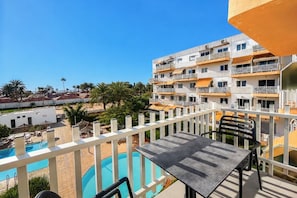 Ein Balkon mit Pool, Gartenmöbeln und Blick auf ein mehrstöckiges Gebäude mit Balkonen.