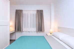 Une chambre d’hôtel avec un lit, une table de chevet avec une lampe et une fenêtre avec des rideaux.