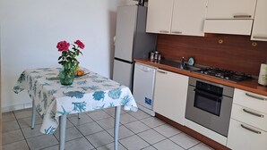 A kitchen with white cabinets, a wooden countertop, a built-in oven, and a small dishwasher.
