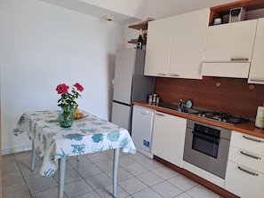 Una cocina con gabinetes blancos, encimera de madera, horno empotrado y lavavajillas pequeño.