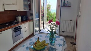 A kitchen with a stove, oven, and a table with a vase and bananas.