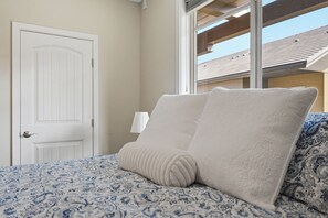 A bedroom with a bed, a white door, a window, and a view of the outside. - 3BR Condo | Lake & Pool Views | Beach Resort (West Kelowna)