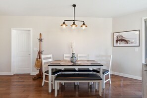 A dining area with a table, chairs, a vase, and a hanging light fixture. - 3BR Condo | Lake & Pool Views | Beach Resort (West Kelowna)